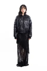 Campera bomber negra de tela satinada con cierre frontal, cuello redondo y puños y cintura elastizados. Tiene un pequeño logo bordado en el pecho y un bolsillo con cierre en la manga. Es reversible.