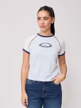 Remera azul marino de algodón con mangas cortas raglán blancas con ribete naranja y estampado ovalado con el logo de Rusty en el pecho.