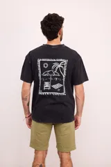 Remera negra con efecto gastado, corte amplio y estampado blanco en el pecho con motivos playeros.