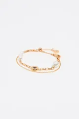 Pulsera dorada de doble cadena, una de eslabones y otra con perlas. Incluye un dije redondo con un corazón negro y logo grabado.