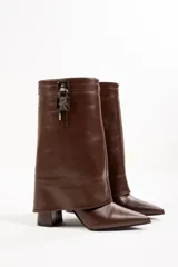 Bota de cuero color beige con punta fina, taco de 10cm y detalle de candado plateado en la caña.