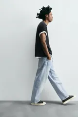 Pantalón de jean gris oscuro, corte amplio, con cinco bolsillos, efecto lavado y cierre frontal con cremallera y botón.