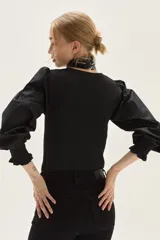 Top negro de calce al cuerpo con escote cuadrado amplio. Mangas largas abullonadas con puños elastizados.