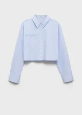 Camisa corta de popelina de algodón a rayas verticales celestes y blancas, con cuello camisero, mangas largas con puños abotonados, bolsillo de parche en el pecho y cierre frontal con botones.
