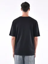 Remera gris de corte oversized, cuello redondo y mangas cortas. 
