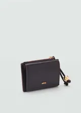 Monedero pequeño color beige con efecto piel y detalle de abalorios. Tiene cierre de solapa con botón magnético, bolsillo interior y bolsillo lateral con cierre de cremallera.