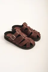Sandalias bajas de cuero marrón con tiras entrecruzadas y hebilla lateral.