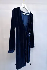Vestido corto de terciopelo azul marino, con escote cruzado en V, mangas largas y lazo lateral ajustable.