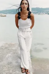 Top blanco de algodón con escote redondo y tirantes decorados con apliques de flores negras.