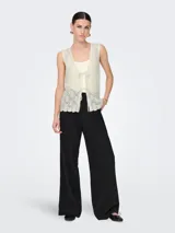 Chaleco de punto color crema con escote en V y lazo delantero. Diseño estructurado y calce ajustado.