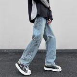 Jean de mezclilla celeste con apliques de estrellas bordadas en los laterales de las piernas. El corte es ancho y holgado, con elástico en la parte trasera de la cintura.