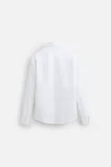 Camisa blanca de algodón, corte slim fit, cuello italiano, manga larga con puños abotonados y cierre frontal con botones.
