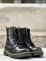 Bota negra de cuero charol con cordones, suela track color caramelo y tirador trasero.