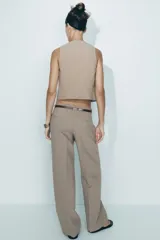 Pantalón de tiro alto con estampado a cuadros en tonos beige y marrón, con bolsillos delanteros y falsos bolsillos traseros. Incluye cinturón marrón con hebilla metálica.