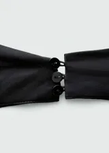 Top negro con escote halter drapeado, espalda abierta y bajo asimétrico.