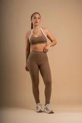 Conjunto deportivo color marrón, compuesto por un top con tirantes blancos y calzas largas con bolsillos laterales.