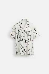 Camisa blanca con estampado abstracto en negro, de cuello bowling y manga corta.