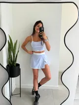 Conjunto deportivo lila compuesto por un top corto con tirantes finos y una minifalda con short incorporado.