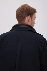 Camisa negra de manga larga con cuello clásico y cierre frontal con botones. Tiene un bolsillo de parche en el pecho izquierdo.