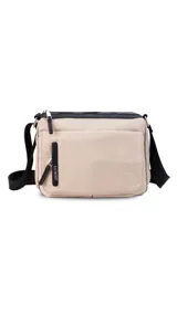 Bandolera color beige de nylon, con correa larga negra regulable. Tiene un bolsillo delantero con tapa, dos bolsillos internos (uno con cierre) y un bolsillo trasero.