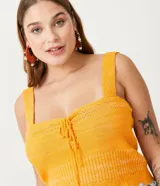 Blusa cropped de punto color amarillo, con tirantes anchos y escote con cordón.
