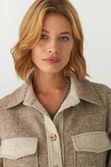 Camisa estilo leñador color beige con textura de espiga, de manga larga con puños abotonados, cuello clásico, cierre frontal con botones y dos bolsillos de parche con solapa abotonada en el pecho.