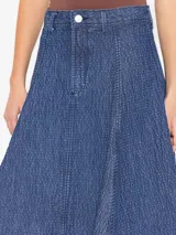 Pollera larga de denim azul con textura en relieve y desgastes, corte acampanado y calce a la cintura.