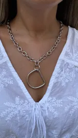 Collar de eslabones grandes con dije en forma de estribo, elaborado en niquel.