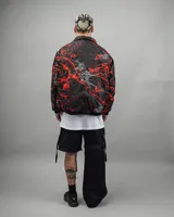 Campera reversible negra con estampado abstracto en rojo y blanco, de corte amplio y cuello camisero.