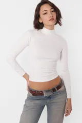 Top color beige de media polera y manga larga, confeccionado en tela de punto ribb con acabado gamuzado, calce slim fit y recorte en laterales.