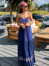 Vestido largo azul con breteles finos y bordado floral en el frente y ruedo.