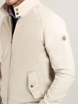 Cazadora tipo bomber color beige, con cierre frontal y bolsillos de solapa.