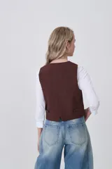 Chaleco negro de poliéster con escote en V y cierre frontal de botones. Diseño holgado.