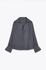 Camisa gris de satén con cuello solapa, escote en pico, mangas largas abullonadas y cierre frontal con botones metálicos.