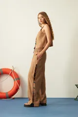Pantalón marrón claro de rayon flex, corte recto, con cintura elastizada y cordón ajustable. Presenta aberturas laterales con mostacillas de colores.