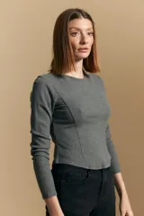 Remera blanca de manga larga con tejido acanalado, cuello redondo y corte ajustado al cuerpo. Presenta costuras verticales que definen la silueta.