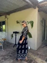 Vestido largo negro con estampado de flores blancas, mangas cortas y corte amplio.