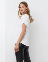 Blusa blanca de manga corta con cuello a la base, confeccionada en tejido crepe.