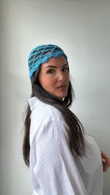 Gorro tipo cofia de crochet color celeste, con diseño de red y borde ondulado.