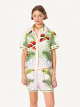 Camisa de satén estampado con diseño tropical de hojas y flores sobre una base geométrica. De manga corta, silueta relajada, cuello clásico y abotonadura central oculta.