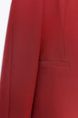 Blazer rojo de escote pico y manga larga. Bolsillos de vivo en delantero. Cierre frontal con botones a presión.