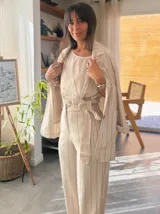 Blazer de lino color crudo con rayas verticales finas en color azul marino, con solapas clásicas, cierre con dos botones de madera y bolsillos delanteros.