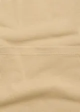 Mono largo color beige, de tirantes finos y corte recto. Incluye cinturón ancho de cuero marrón con hebilla plateada.