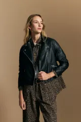 Campera negra de cuero sintético estilo biker, con cierre asimétrico, broches metálicos en el cuello y bolsillos con cierre.