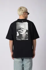Remera negra oversize de algodón premium con cuello redondo y mangas cortas. Presenta un logo bordado en el frente y un parche estampado en la espalda.