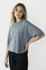 Remera gris oscuro de corte holgado con estampado de una estrella naranja en el pecho.