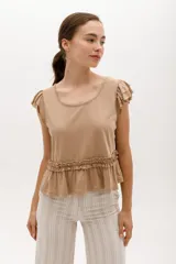 Remera color beige con cuello redondo, mangas cortas con volados y frunce con volados en la cintura.