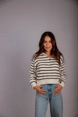 Sweater de punto color beige con rayas horizontales blancas, cuello polo con cierre de cremallera y mangas largas.