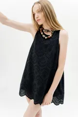 Vestido corto negro con bordado calado, sin mangas y corte evasé.