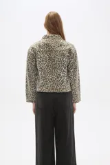 Chaqueta corta de jean con estampado animal print en tonos beige y gris, cuello camisero, cierre frontal con cremallera, bolsillos de parche en el pecho y corte entallado.